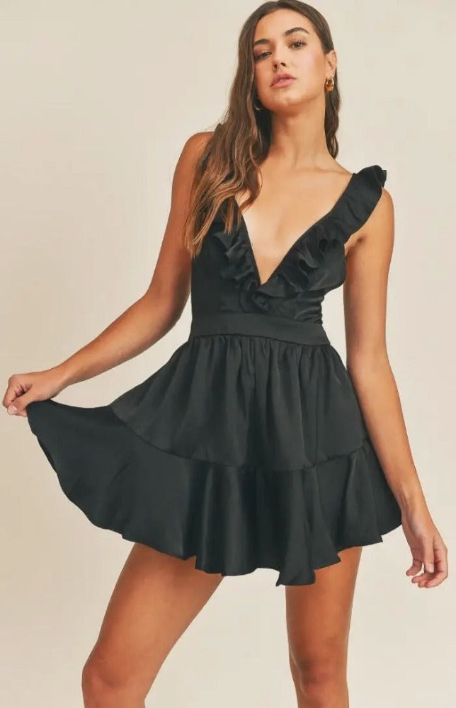 Don't be surprised if secret admirers make themselves known when you step out in the Anastasia V-Neck Satin Ruffle Playsuit! Romantic black satin comes together to form a deep ruffled V-neckline and fitted bodice. A sexy lace up detail delicately crosses the back, finishing with tailored shorts that end with ruffled hems. 