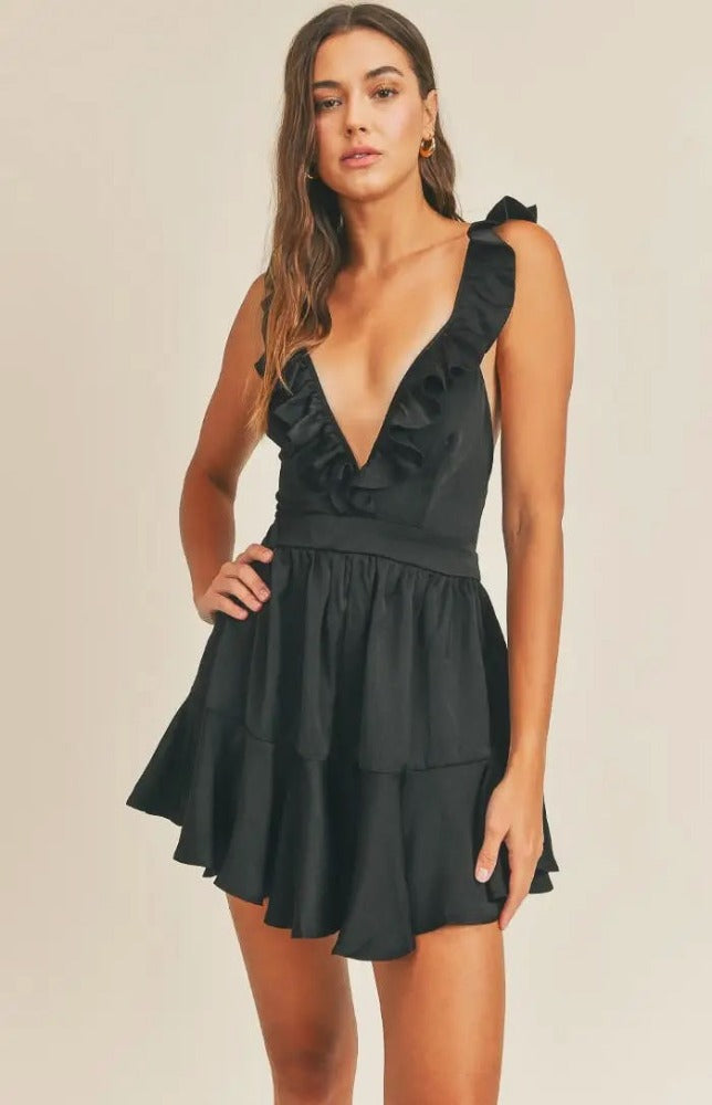 Don't be surprised if secret admirers make themselves known when you step out in the Anastasia V-Neck Satin Ruffle Playsuit! Romantic black satin comes together to form a deep ruffled V-neckline and fitted bodice. A sexy lace up detail delicately crosses the back, finishing with tailored shorts that end with ruffled hems. 