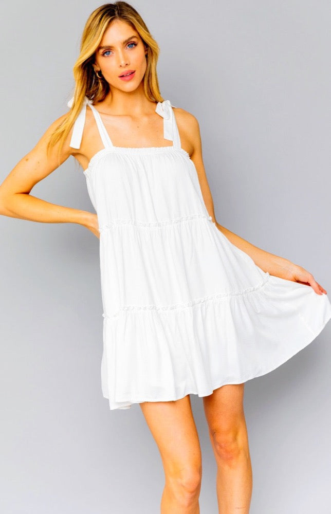 Outdoor events call for outdoor styles like the Denise Dress in white. Woven fabric shapes this dress that has adjustable tie straps, a straight elasticized neckline. A high waist tops a tiered mini skirt. Pair this cutie with espadrilles and a big floppy hat to take the look all the way! 