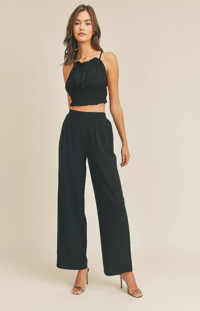 Take it easy in the Remi Halter Crop Top and Palazzo Pants Set in Black! Woven fabric shapes this sleek and casual set that includes a ruched-detail crop top with a halter neckline, and lace-up back. Matching high-waisted Palazzo pants have wide, tulip pant legs and side pockets.