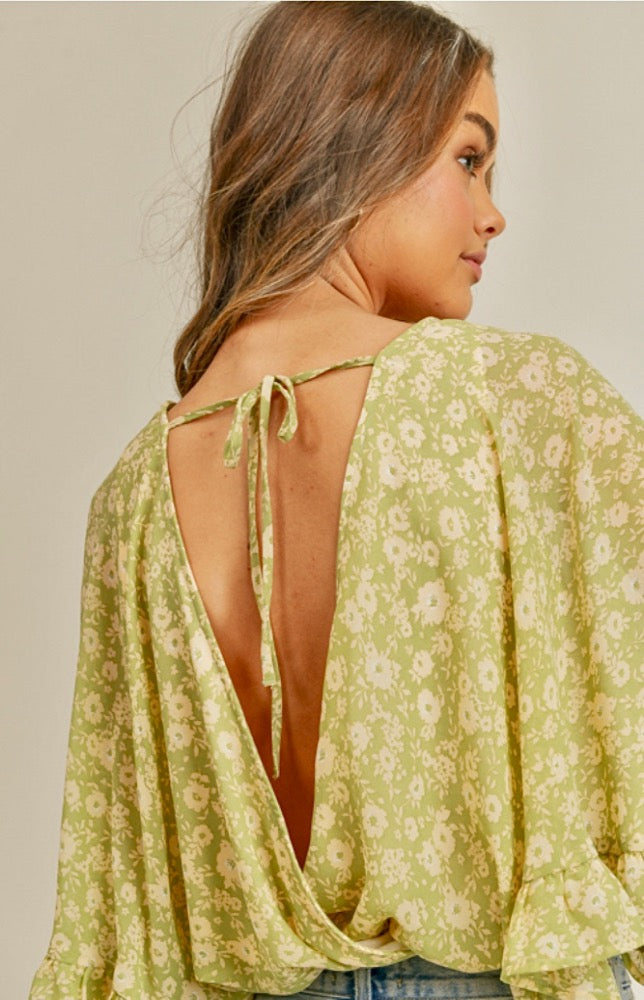 You will definitely bring the sunshine when you wear the Ravae Flutter Sleeve Backless Bodysuit! Lightweight woven celery colored fabric shapes this angelic bodysuit that has a deep V-neckline. She has a beautiful butter colored floral design.  The Ravae is framed with fluttery short sleeves with hidden lining at the side. The attached stretch knit bottoms have cheeky coverage and snap closures.