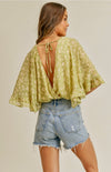 You will definitely bring the sunshine when you wear the Ravae Flutter Sleeve Backless Bodysuit! Lightweight woven celery colored fabric shapes this angelic bodysuit that has a deep V-neckline. She has a beautiful butter colored floral design.  The Ravae is framed with fluttery short sleeves with hidden lining at the side. The attached stretch knit bottoms have cheeky coverage and snap closures.