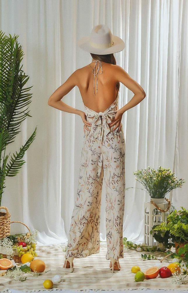 Let the breeze take you away in this floral printed halter neck jumpsuit. This lovely jumpsuit has adjustable ties at the neck and mid-back allowing you to tighten to your comfort. The low cut V-neckline leads to a fitted bodice and casual wide leg pants.