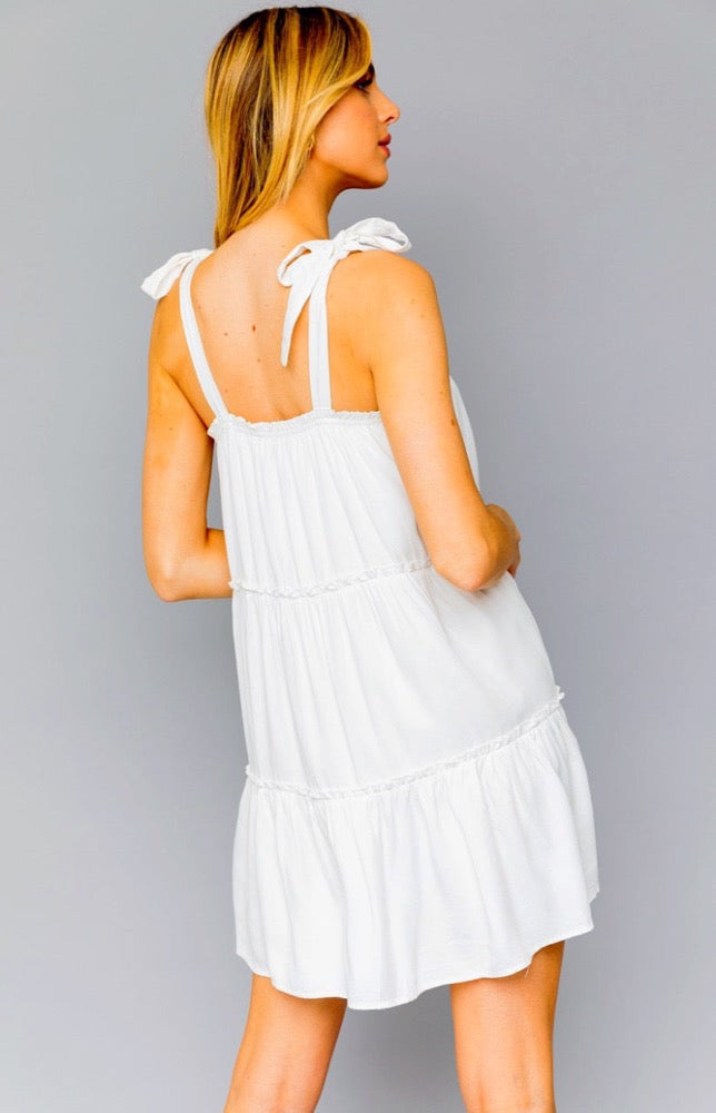 Outdoor events call for outdoor styles like the Denise Dress in white. Woven fabric shapes this dress that has adjustable tie straps, a straight elasticized neckline. A high waist tops a tiered mini skirt. Pair this cutie with espadrilles and a big floppy hat to take the look all the way! 