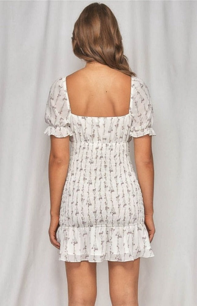 The Zoe Dainty Floral Shirred Dress in white will have you imbued romance. The delicate floral print highlights the details from the puff sleeves with ruffled arm band to the sweetheart neckline. The shirred bodice leads to a fun and flirty loose ruffle hem. This effortless, lightweight piece can go from day to night, city to beach.